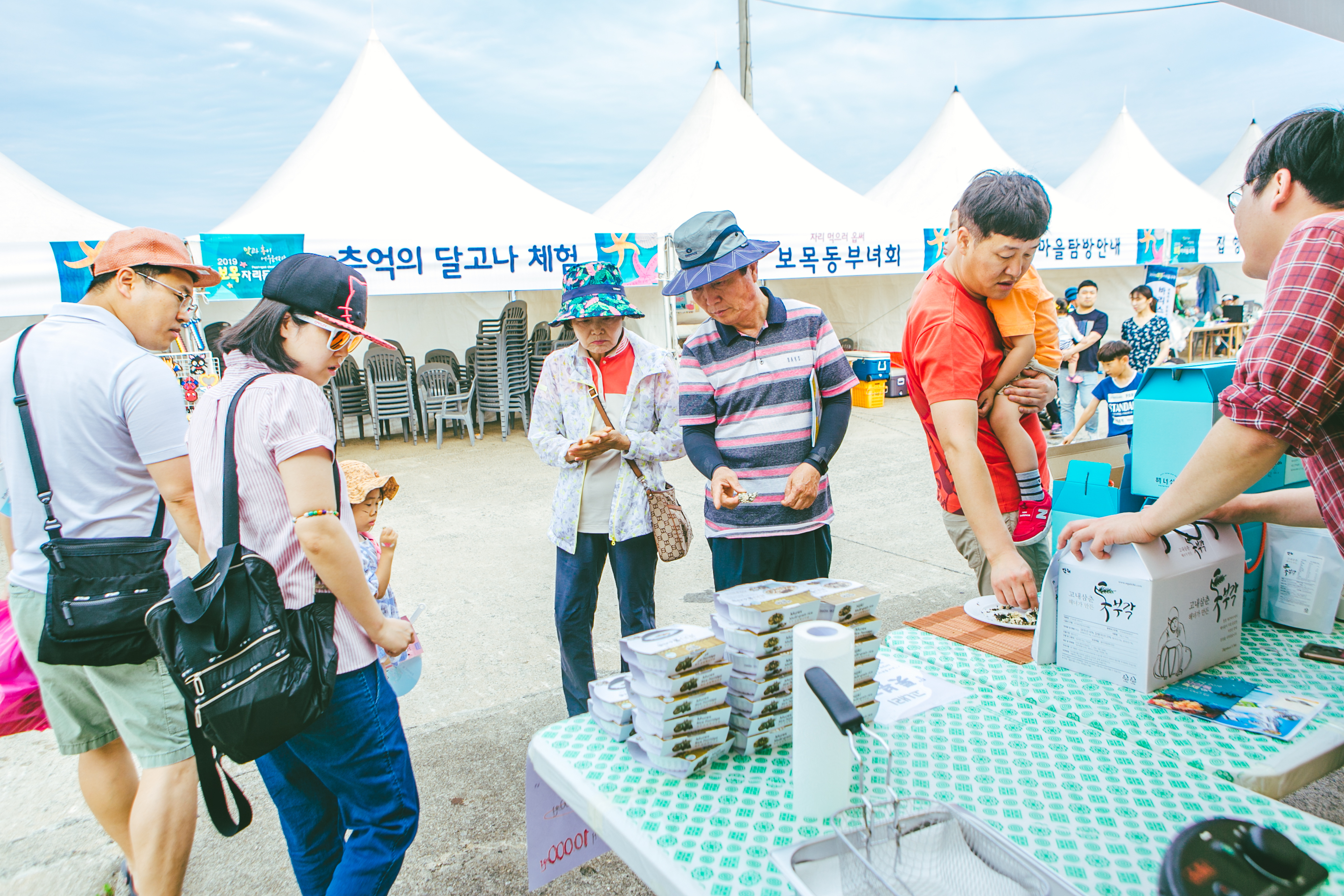보목자리돔 축제 - 판매자는 제품을 설명하고, 방문객들은 제품을 바라보는 사진