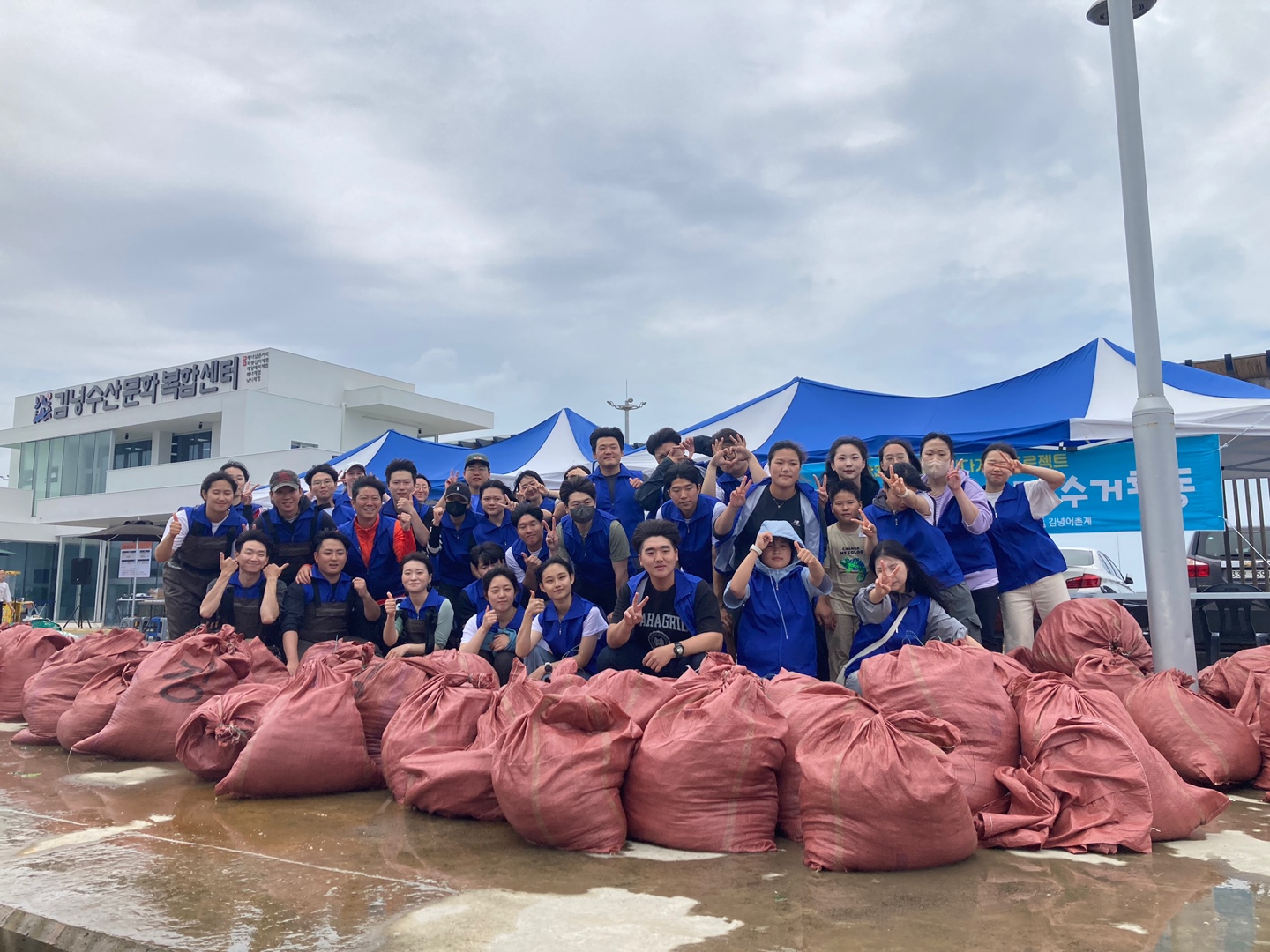 제1회 바다가 꿈 프로젝트(김녕) - 쓰레기포대 뒤에서 단체사진을 찍고 있는 사진