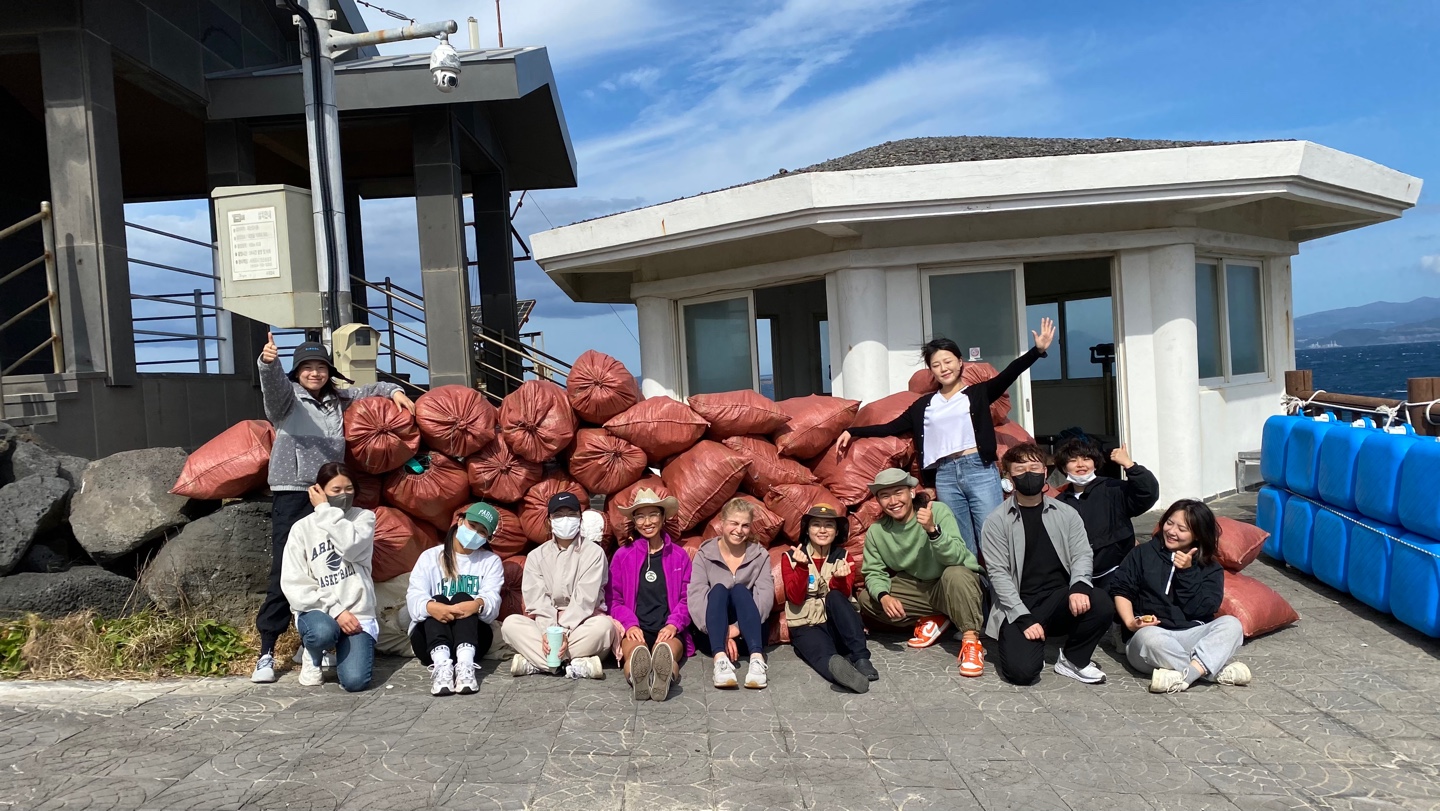 제9회 바다가꿈 프로젝트  해안가에서 수거한 쓰레기 더미를 배경으로 찍은 단체사진